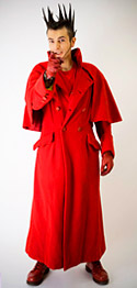 Photo de Vaquette dans un grand manteau rouge qui pointe son index en avant : grrr !
